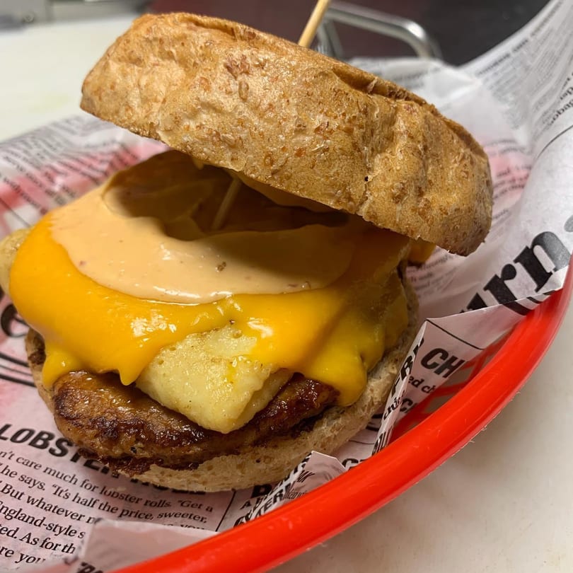 Bushwick Burger Co. burger with melted cheese, sauce, and hash browns in a red basket.