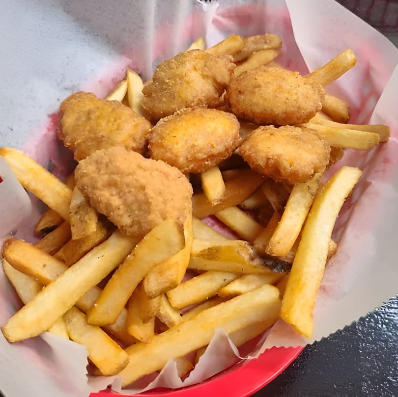 Golden-brown chicken nuggets and crispy french fries served in a red basket lined with white paper.